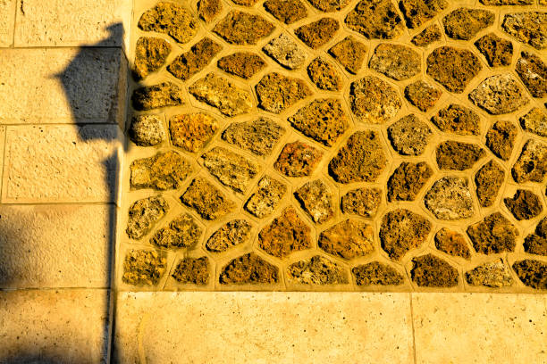 Shadow of Paris street lamp in early morning sun against stone wall in Montarte